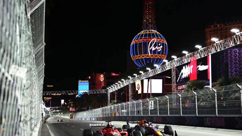 Formula 1 cars racing down the Las Vegas Strip past the Paris balloon at night